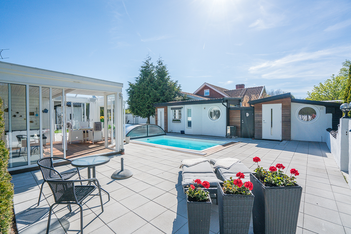 Inramad poolmiljö med stor stensatt terrass