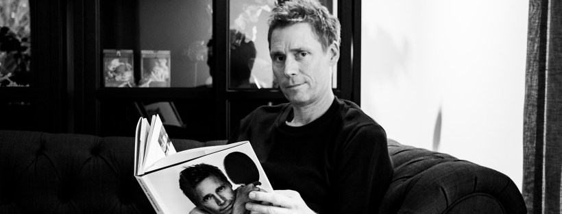 Jörgen Persson bläddrar i sin biografi med det egna porträttet på framsidan "Den snälla Världsmästaren" av Jens Fellke och Helena Egerlind.